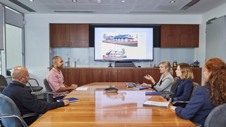 Meeting in boardroom with building image on screen